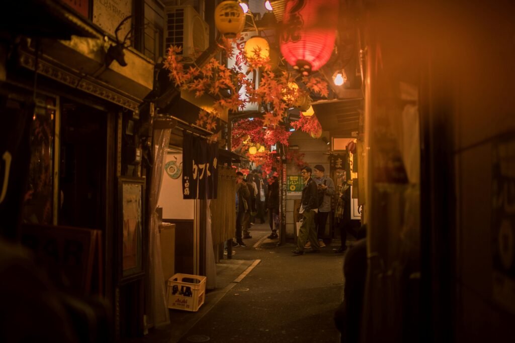 Bustling Tokyo street scene at night with paper lanterns and people.