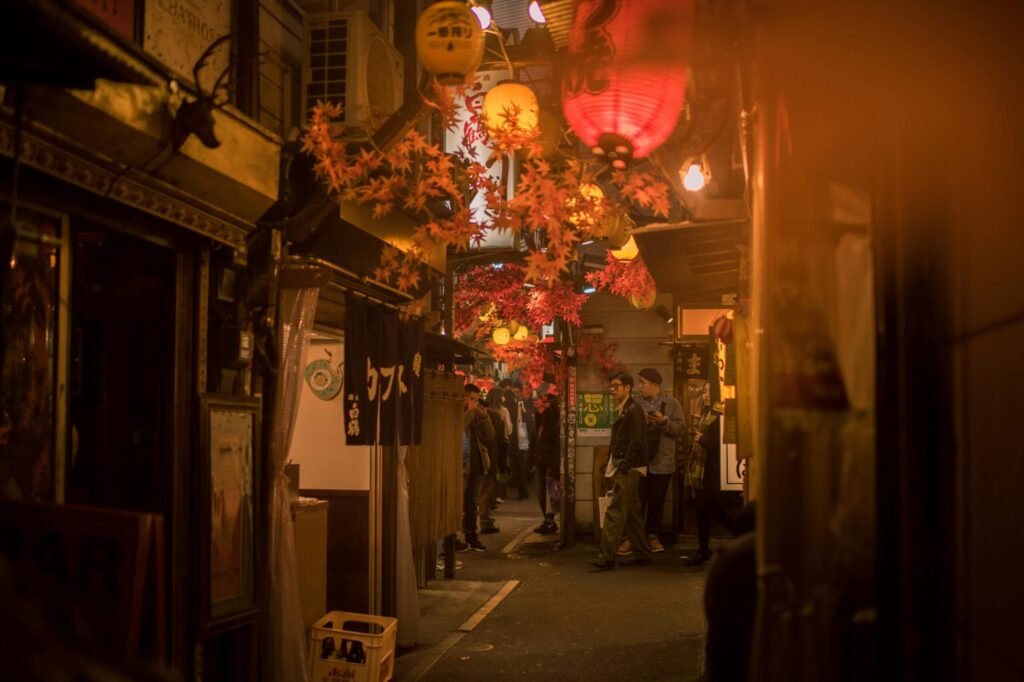 Bustling Tokyo street scene at night with paper lanterns and people.