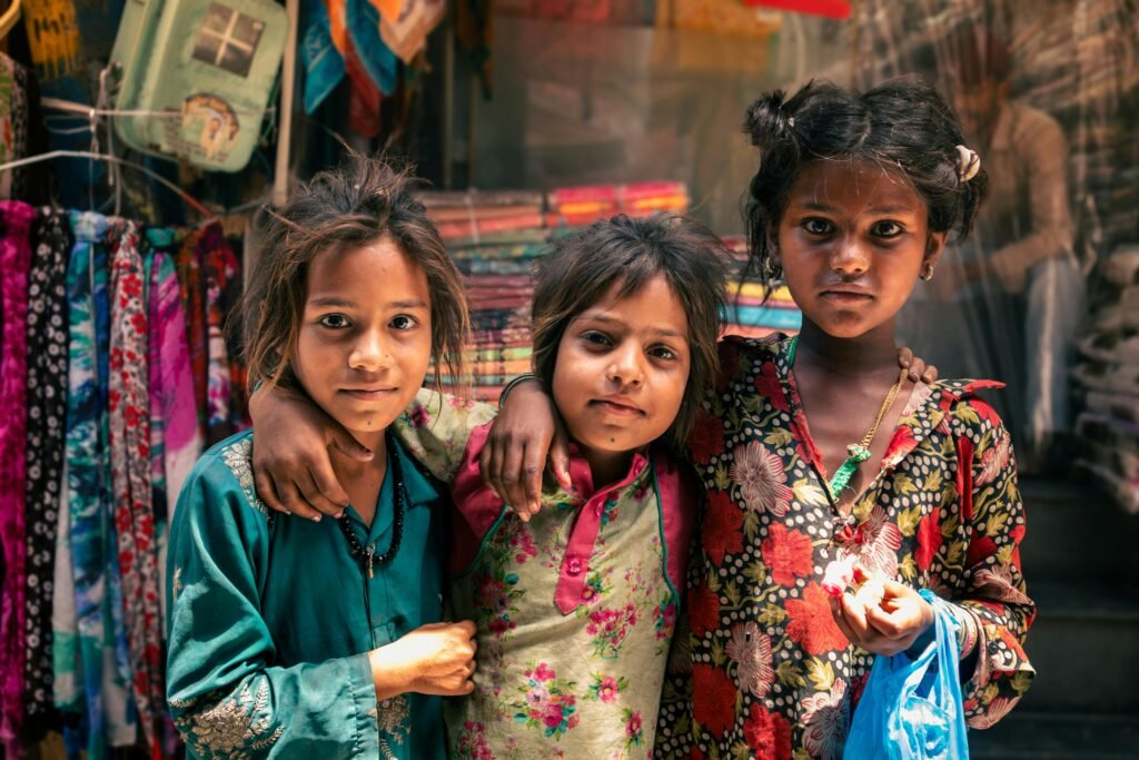 A group of three children in vibrant traditional attire posing in Jalandhar market street.