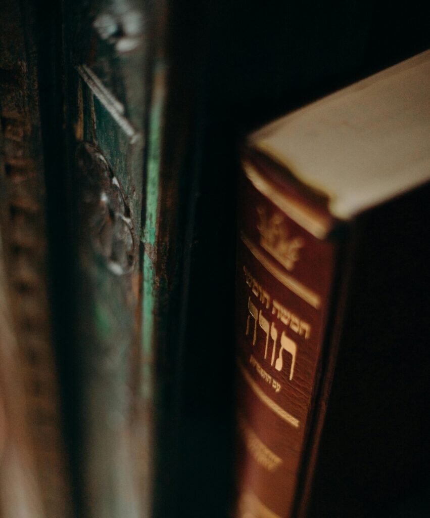 Close-up of a vintage Torah book with Hebrew text on a dark bookshelf, evoking tradition and wisdom.